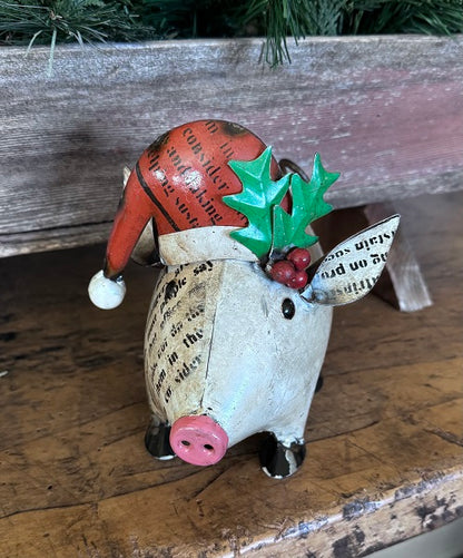 Decorative Christmas pig figurine with a red hat and holly leaves on a wooden surface.