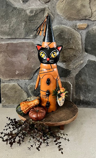 Halloween-themed cat figurine with a witch hat against a stone wall background