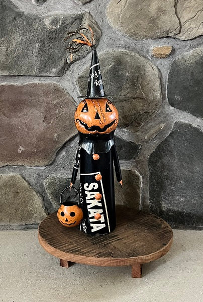 Halloween-themed decoration with a pumpkin and witch figure against a stone wall.