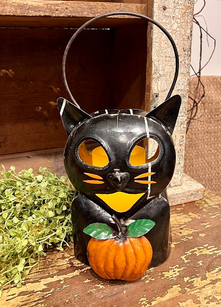Black cat-shaped lantern with a pumpkin on a wooden surface
