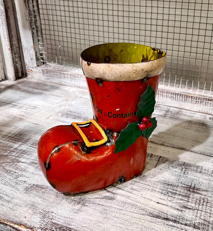 Decorative boot-shaped container with a holly leaf and berry on a wooden surface.