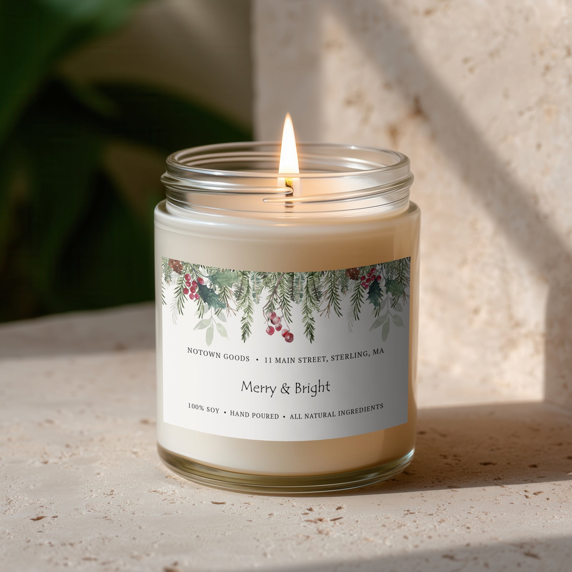 Clear jar candle with white wax and a decorative label on a blurred outdoor background.