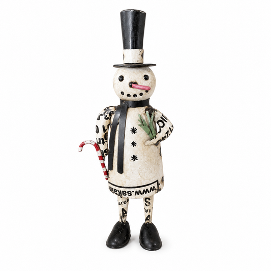 Decorative snowman figurine with a top hat and scarf, standing among stacked firewood and pine branches.