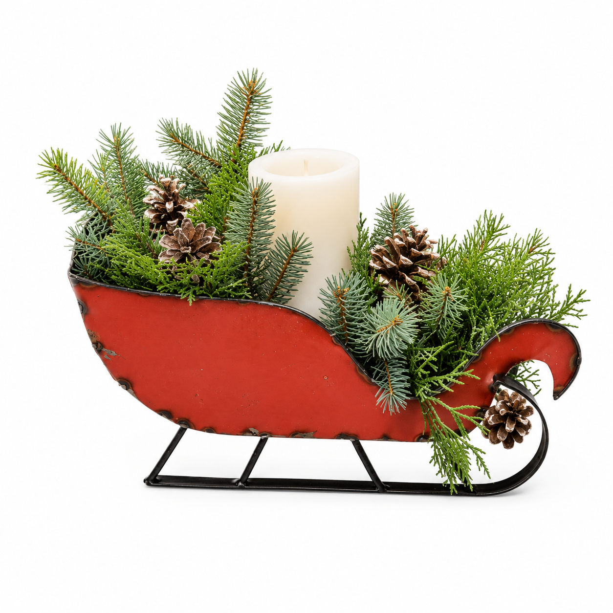 Decorative red sleigh with greenery and a candle on a white background