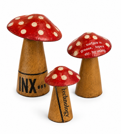 Three red and brown metal mushrooms with white spots on a white background