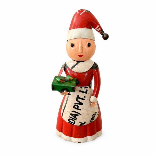 Vintage-style Christmas figure of a woman in a red dress and Santa hat holding a bag and gift.