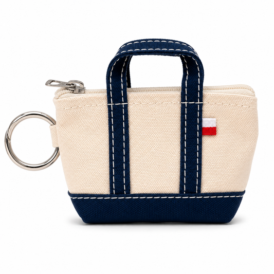 Small beige pouch with navy handle and trim on a white background