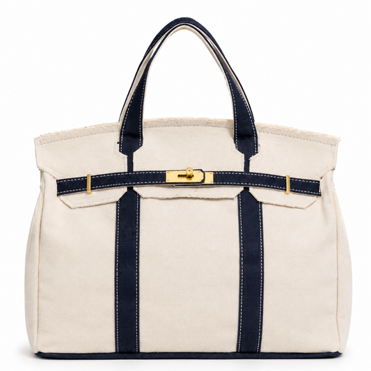 White tote bag with navy straps and a gold tag on a white background
