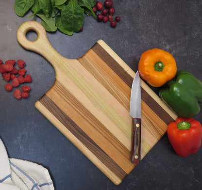 Wooden cutting board with knife and vegetables on a dark countertop