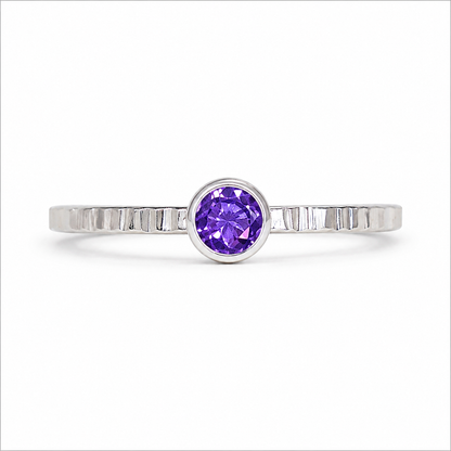 Silver ring with a purple gemstone on a white background