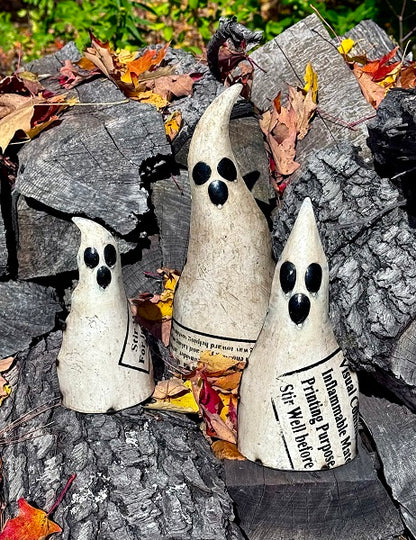 Three metal ghosts on a stone surface with autumn leaves.