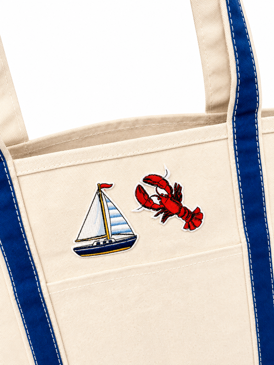 Beige tote bag with sailboat and lobster design on a white background