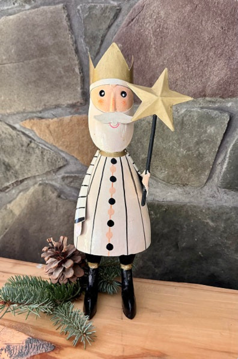 Santa Claus figurine holding a star staff on a stone wall background