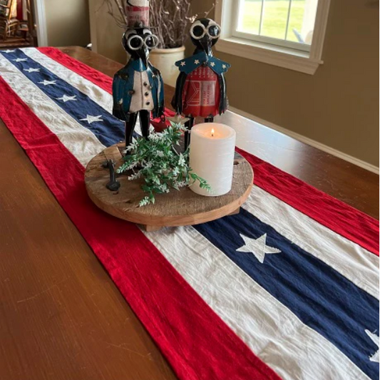 Table setting with American flag table runner, candle, and decorative figures.