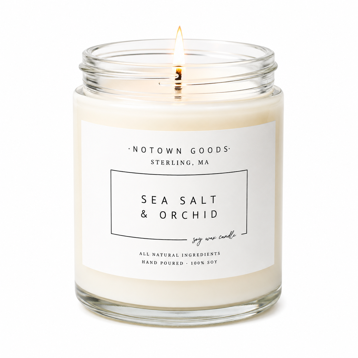 Clear jar candle with white wax and a decorative label on a white background.