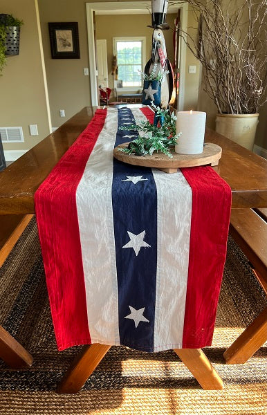Dining room table with a red, white, and blue table runner and decorative items.