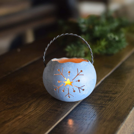Decorative lantern with a lit candle inside on a wooden surface