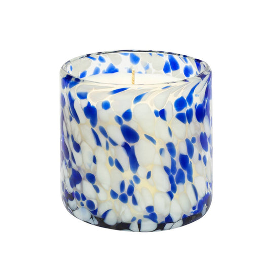 Candle in a blue and white speckled glass container on a white background