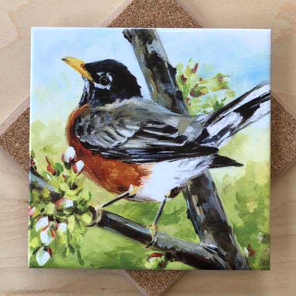Trivet with a painting of a robin on a branch with a natural background.