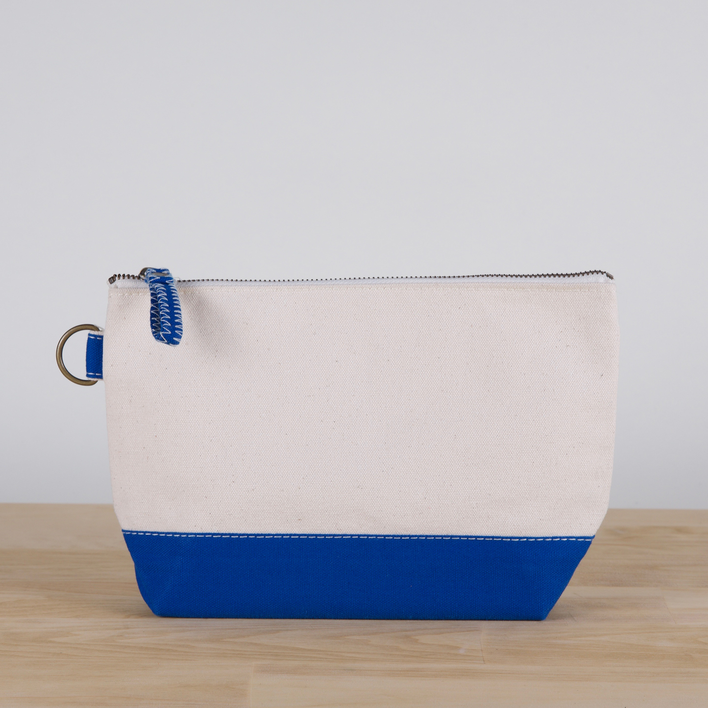 Canvas pouch with blue bottom section on a wooden surface