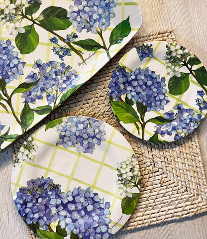 Set of three round plates with blue hydrangea floral design on a woven mat.