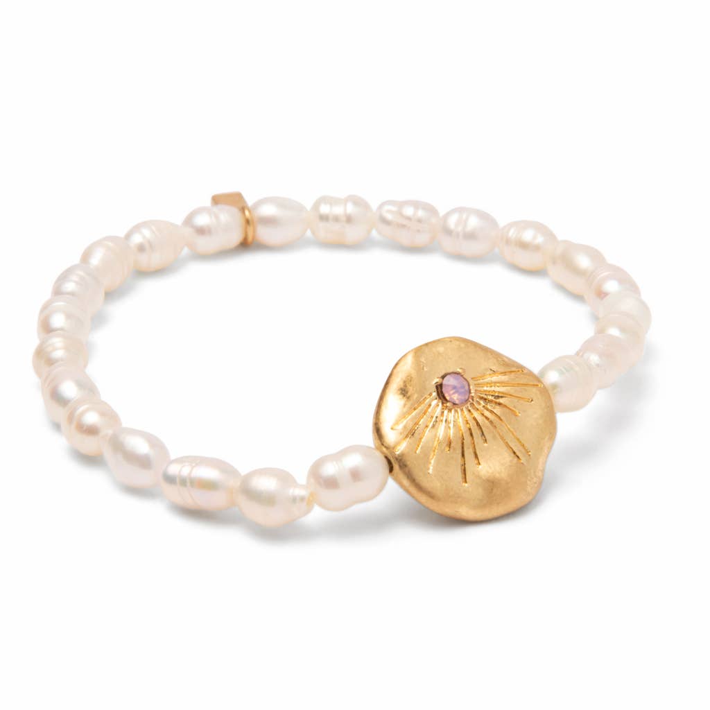 Pearl bracelet with a gold disc and pink gemstone on a white background