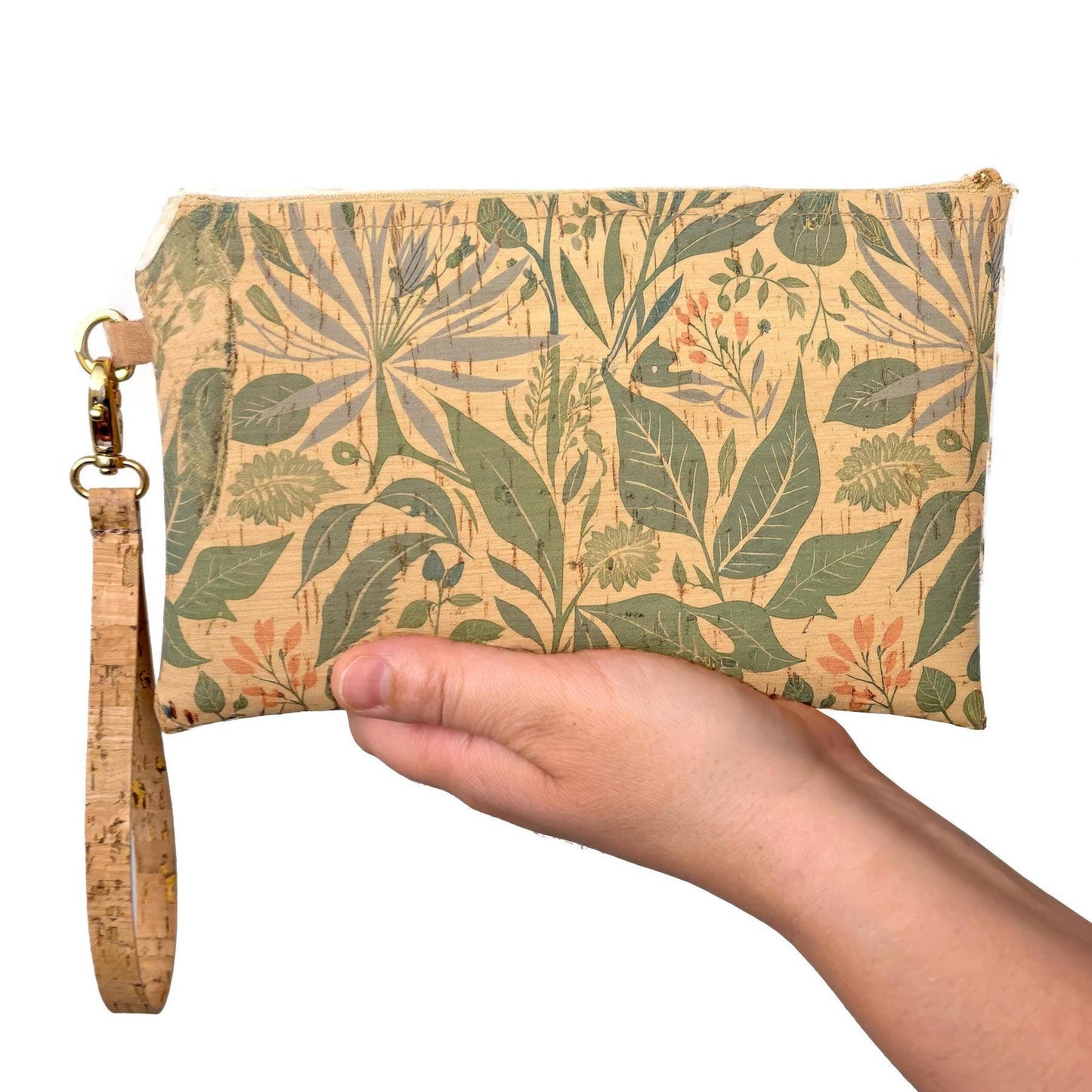 Hand holding a medium wristlet with leaf pattern and cork strap.
