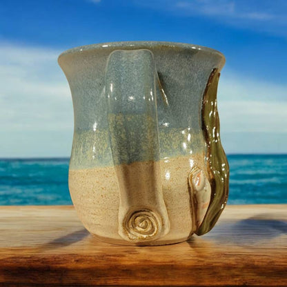 Ceramic mug with sand-like texture on a wooden surface with ocean view