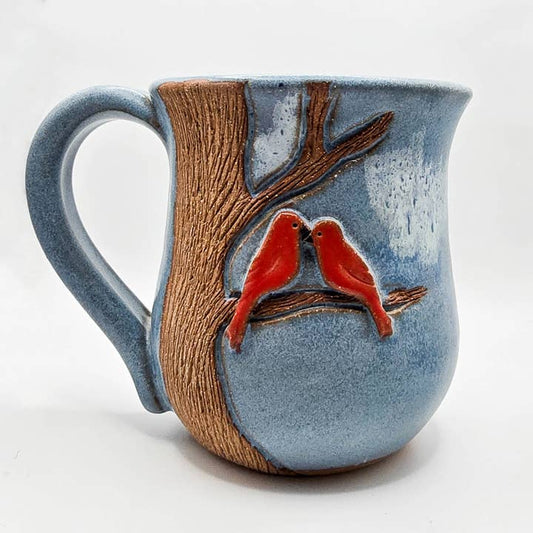 Ceramic mug with tree design and red birds on a white background