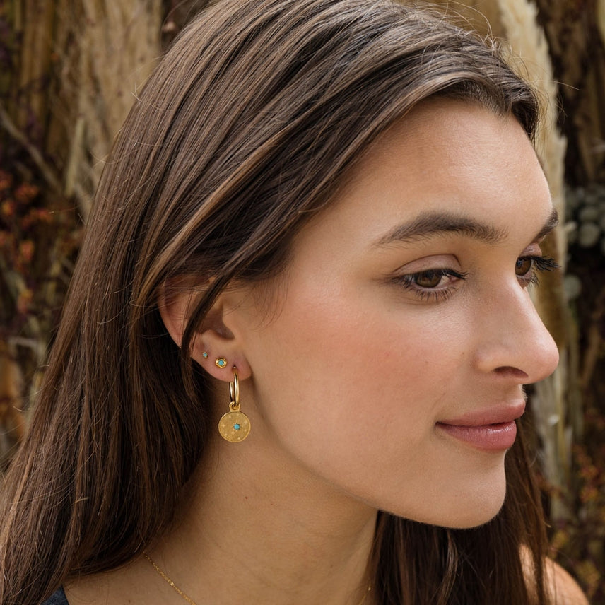 Close-up of a woman wearing gold earrings with a natural background