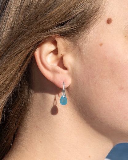 Close-up of an ear wearing a blue teardrop earring.