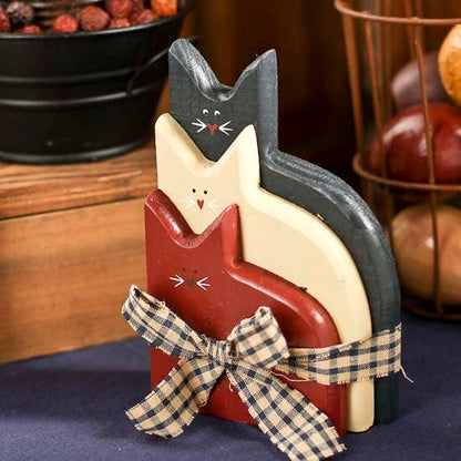 Decorative cat-shaped items with a plaid ribbon on a wooden surface.