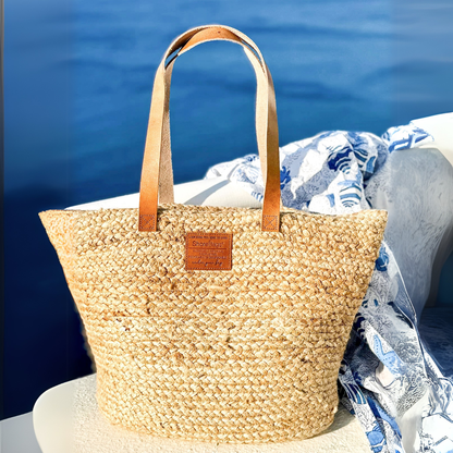 Woven straw bag with leather straps on a boat against a blue water background
