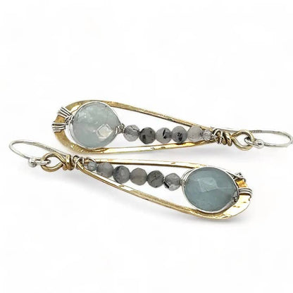 Pair of earrings with gold and silver accents and gemstones on a white background