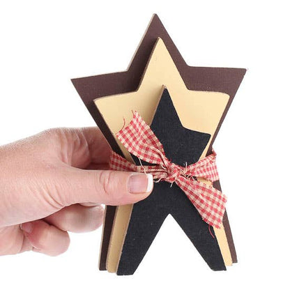 Hand holding a star-shaped wooden ornament with a red and white checkered ribbon on a white background