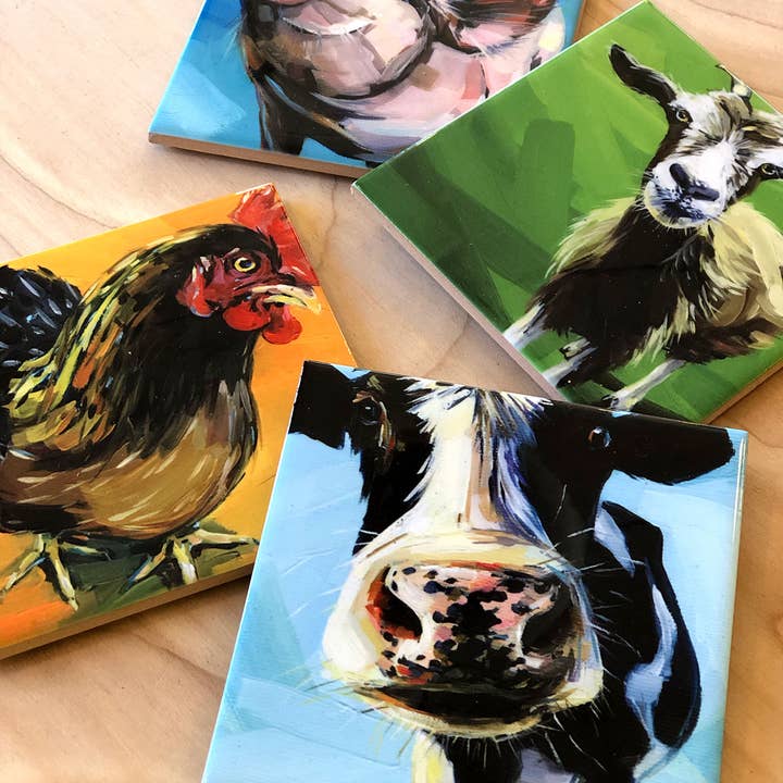 Four colorful coasters featuring animal portraits on a wooden surface.
