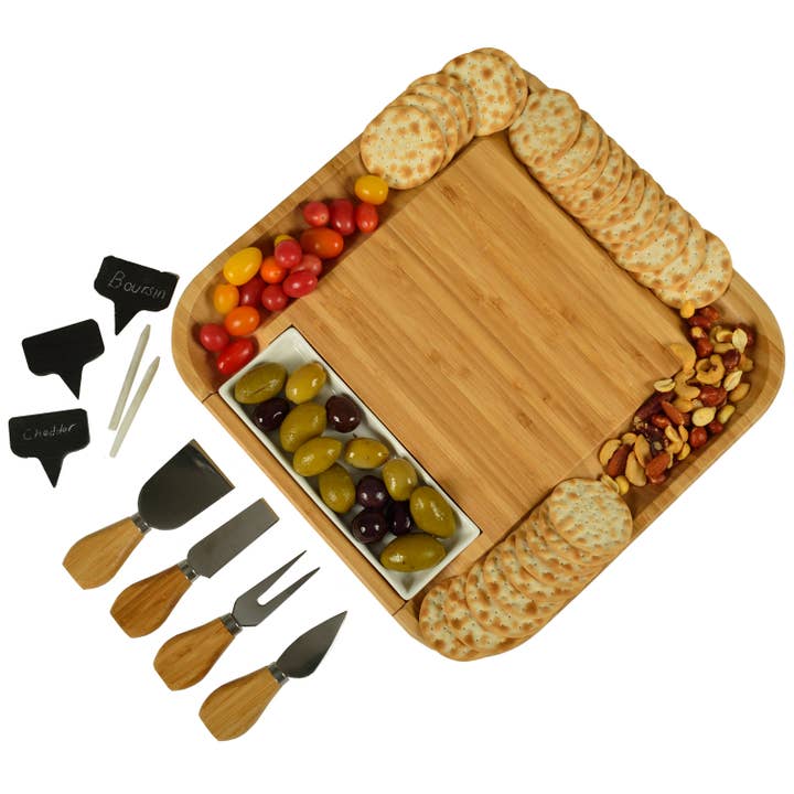 Wooden charcuterie board with assorted meats, cheeses, and accompaniments on a white background