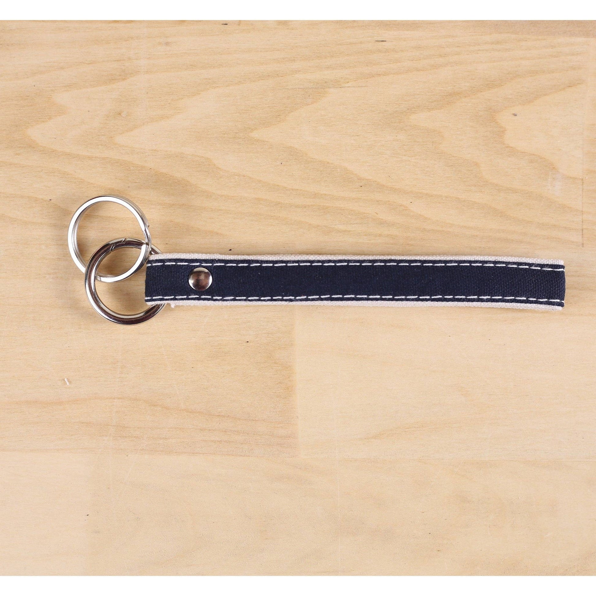 Keychain with navy blue strap and silver rings on a wooden surface