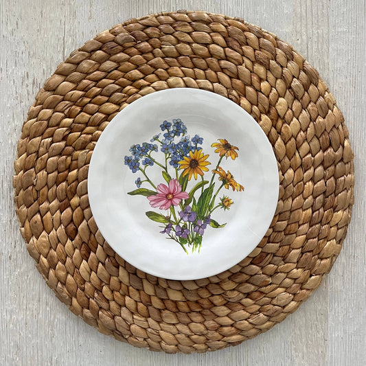 White plate with floral design on a woven placemat