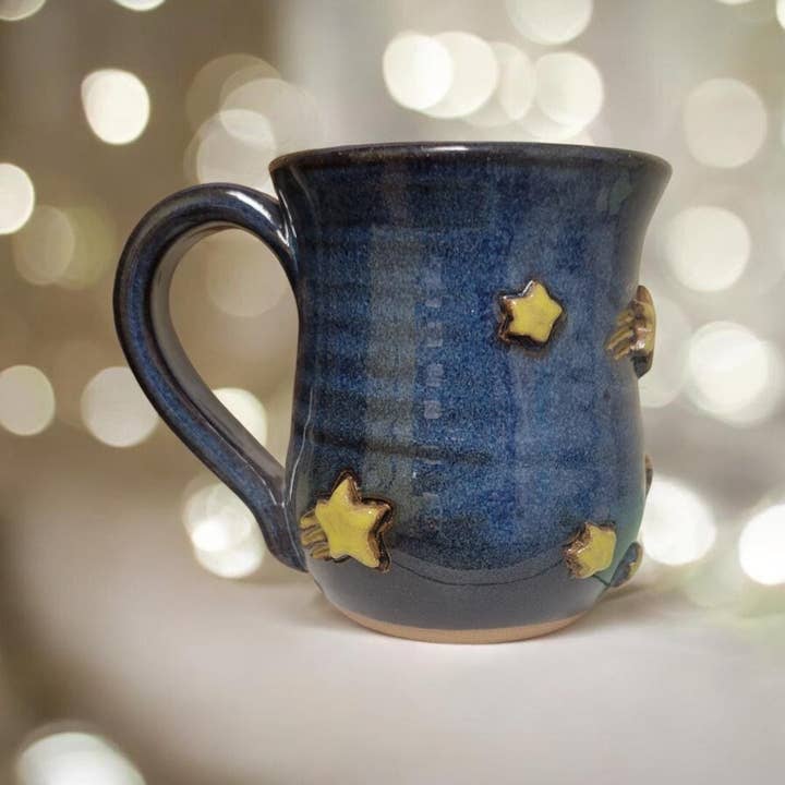 Blue ceramic mug with star designs on a blurred light background
