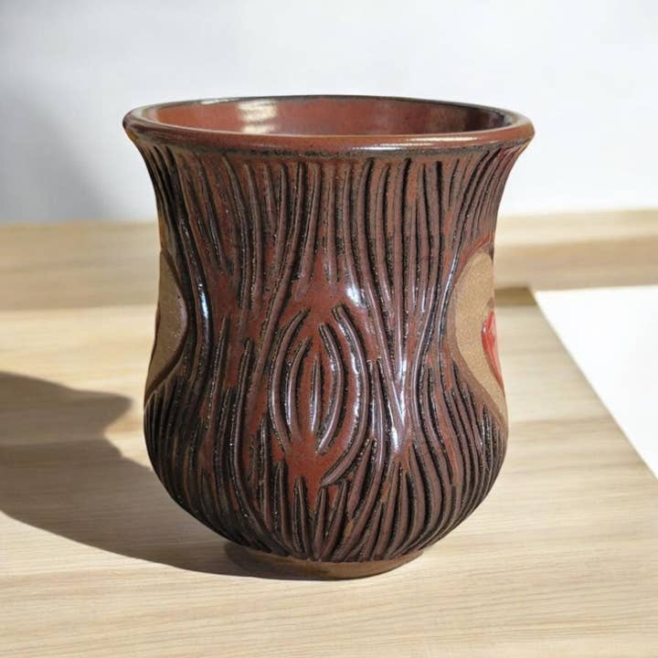 Brown ceramic mug with textured design on a light wooden surface
