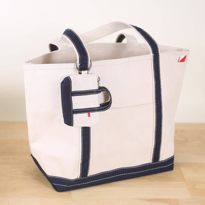 White tote bag with navy trim on a wooden surface