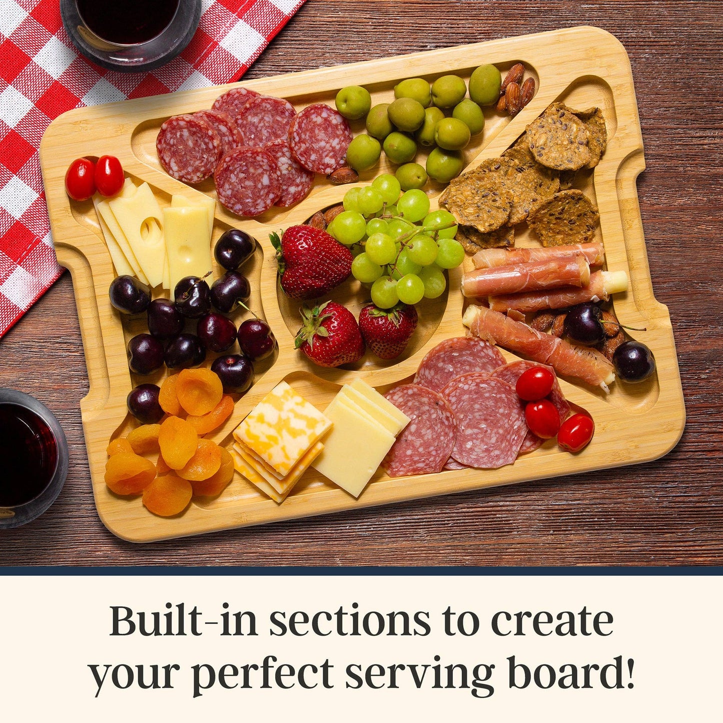 Wooden charcuterie board with various foods including meats, cheeses, fruits, and nuts on a wooden surface. Text at the bottom: Built-in sections to create your perfect serving board!