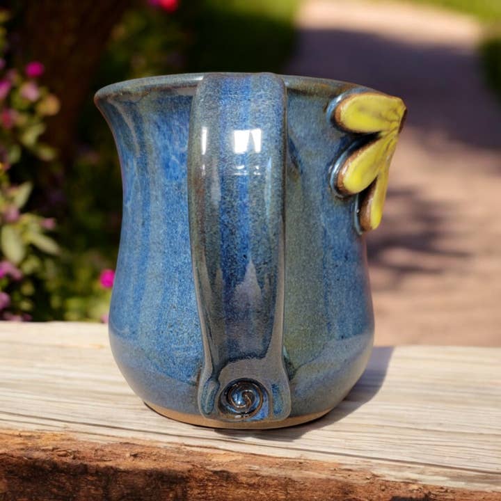 Blue ceramic mug with floral design on a wooden surface outdoors