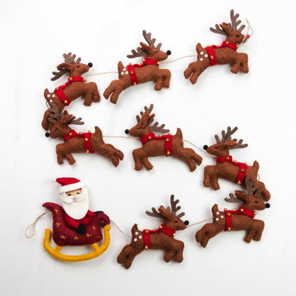Felt Christmas ornament garland featuring brown reindeer with red harnesses and Santa Claus pulling a red sleigh with yellow reins, arranged on a white background.