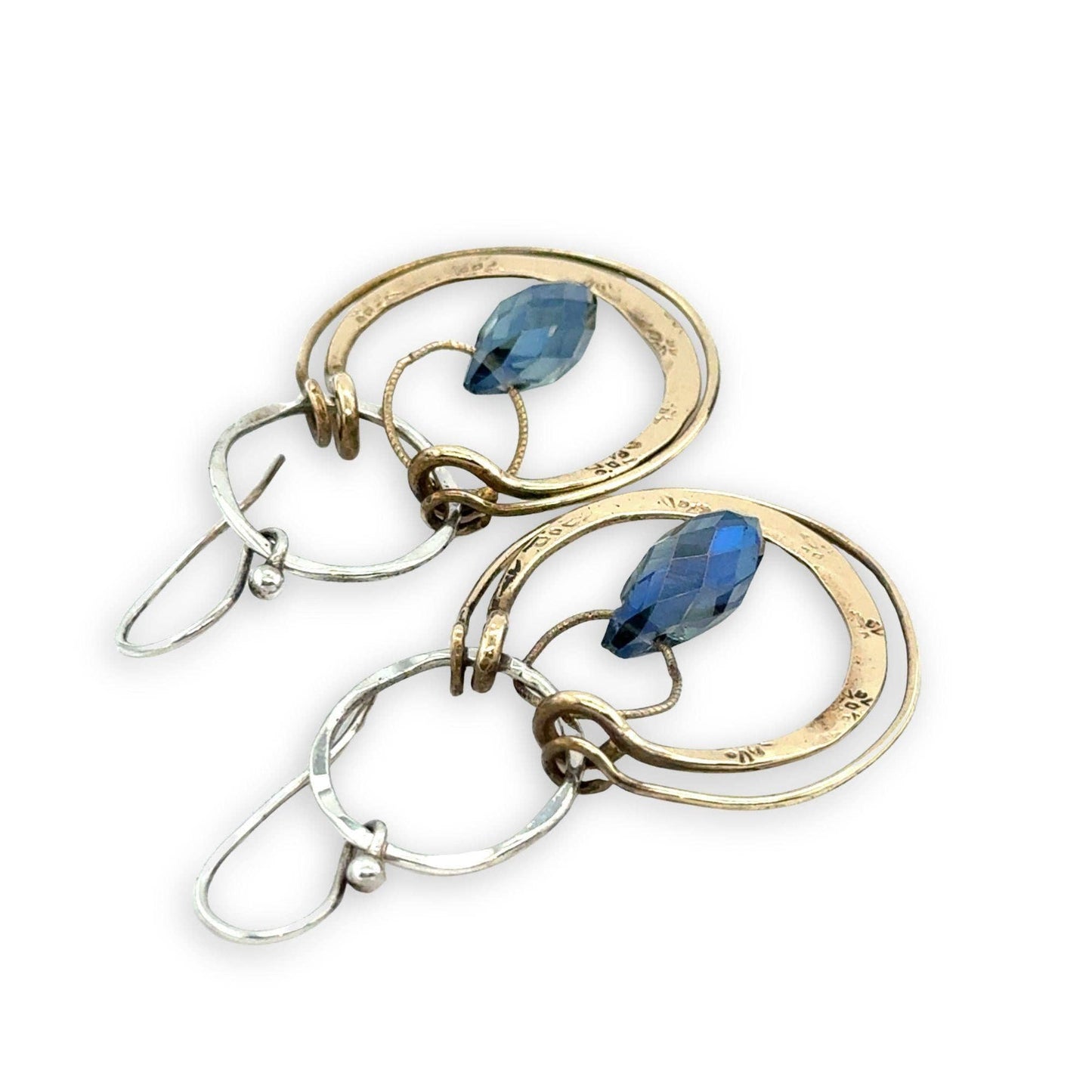 Gold and silver earrings with blue gemstones on a white background