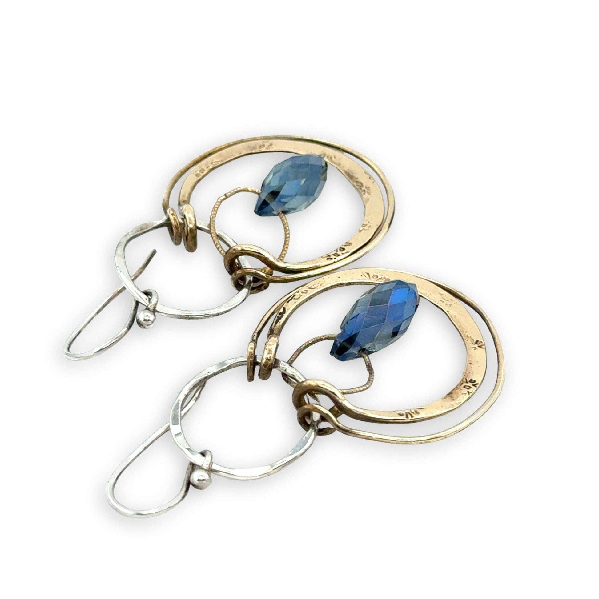 Gold and silver earrings with blue gemstones on a white background