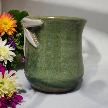 Green ceramic mug with floral arrangement on a white background