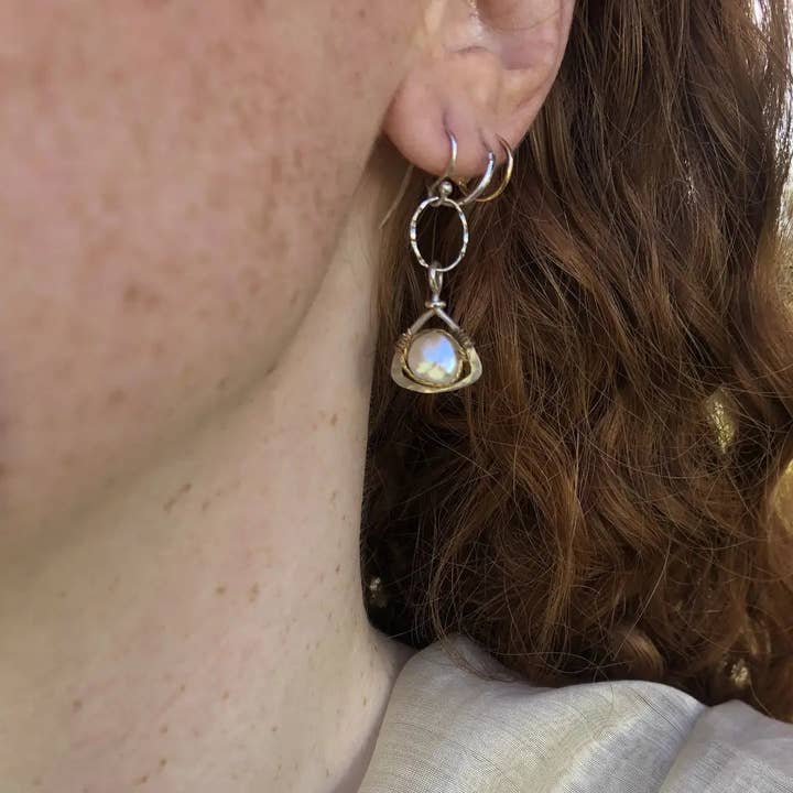 Close-up of a person wearing a silver earring with a pearl.