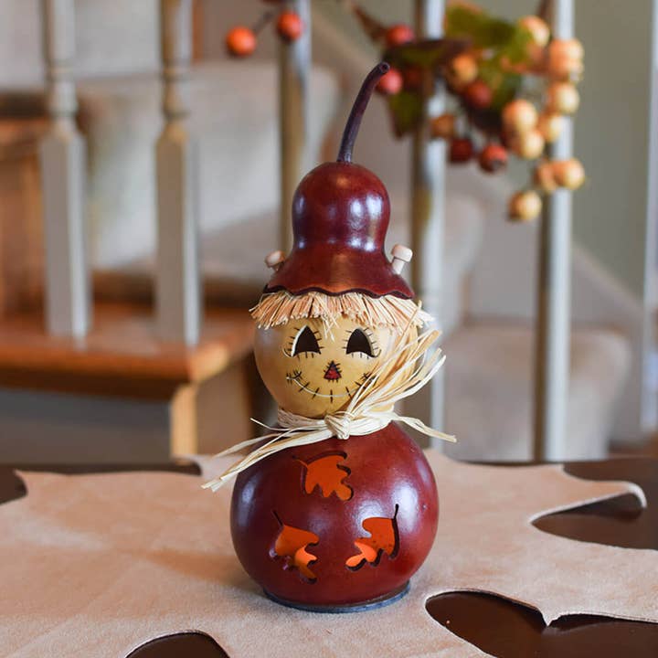 Decorative scarecrow gourd with a face on a table with a blurred background